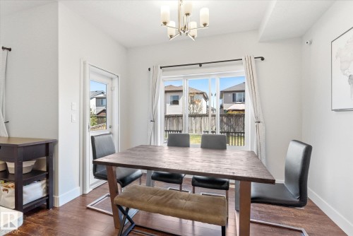 Dining area with wood-finish flooring, a contemporary chandelier, and white walls - 54 Cypress Link, Fort Saskatchewan, AB - Indoor Photo Showing Dining Room