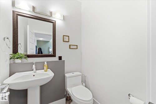 Pedestal sink with chrome faucet, framed mirror, and contemporary vanity lighting fixture - 54 Cypress Link, Fort Saskatchewan, AB - Indoor Photo Showing Bathroom