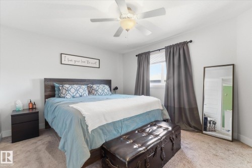 Light-filled bedroom featuring light-colored walls, carpeted flooring, and a ceiling fan with integrated lighting - 54 Cypress Link, Fort Saskatchewan, AB - Indoor Photo Showing Bedroom