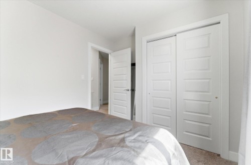 Bright interior space featuring a double-door closet with paneled doors, light-colored walls, and carpet flooring - 54 Cypress Link, Fort Saskatchewan, AB - Indoor Photo Showing Bedroom