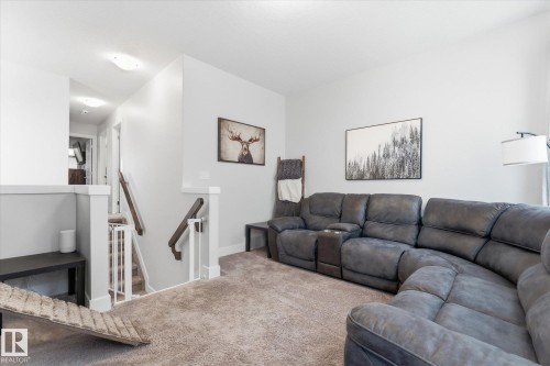 Carpeted upper-level landing featuring a staircase with white balusters and dark wood handrails, recessed lighting, and neutral wall tones - 54 Cypress Link, Fort Saskatchewan, AB - Indoor Photo Showing Living Room