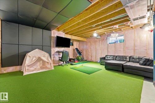 Recreational room featuring green artificial turf flooring, exposed ceiling joists, and sound-absorbing wall panels - 54 Cypress Link, Fort Saskatchewan, AB - Indoor Photo Showing Basement