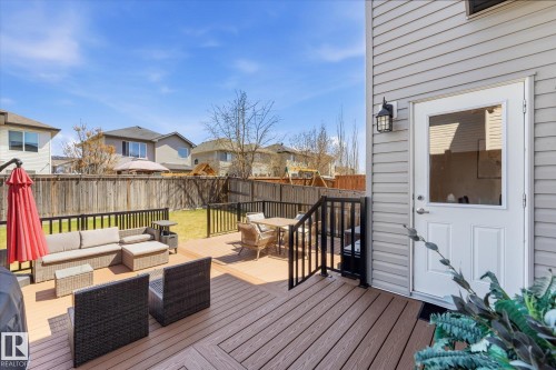 Expansive wood-finish deck featuring dark railings, a privacy fence, and a manicured lawn - 54 Cypress Link, Fort Saskatchewan, AB - Outdoor With Deck Patio Veranda With Exterior
