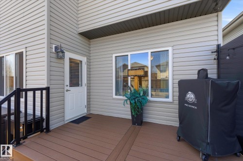 Exterior deck featuring wood-finish composite decking, black metal railings, and light grey siding - 54 Cypress Link, Fort Saskatchewan, AB - Outdoor With Deck Patio Veranda With Exterior