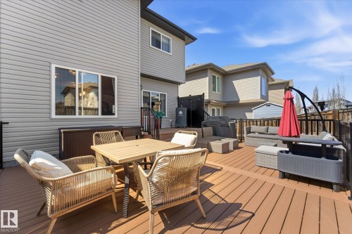Expansive multi-level composite deck featuring dark brown decking, black railings, and direct access to the interior via a sliding glass door - 54 Cypress Link, Fort Saskatchewan, AB - Outdoor With Deck Patio Veranda With Exterior
