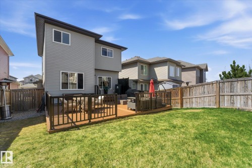 Expansive lawn with a wood-finish deck and dark railings - 54 Cypress Link, Fort Saskatchewan, AB - Outdoor With Exterior