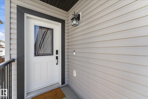 Front entry with a white door featuring a decorative glass insert and black trim - 54 Cypress Link, Fort Saskatchewan, AB - Outdoor With Exterior