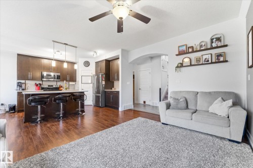 Open-concept living area featuring rich wood-finish flooring, a contemporary ceiling fan, recessed lighting, and an arched doorway - 54 Cypress Link, Fort Saskatchewan, AB - Indoor Photo Showing Living Room