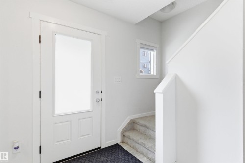 Entryway featuring a white door with frosted glass panel, contrasting dark hardware, and white trim - 9 850 Secord Boulevard, Edmonton, AB - Indoor Photo Showing Other Room