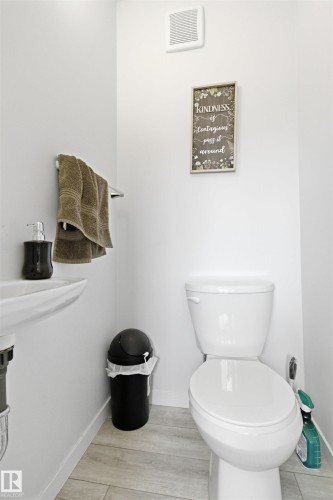 White wall-mounted sink with visible plumbing, complemented by a standard white toilet - 9 850 Secord Boulevard, Edmonton, AB - Indoor Photo Showing Bathroom