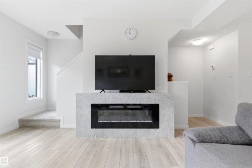 Contemporary electric fireplace with a light-toned stone surround - 9 850 Secord Boulevard, Edmonton, AB - Indoor Photo Showing Living Room With Fireplace