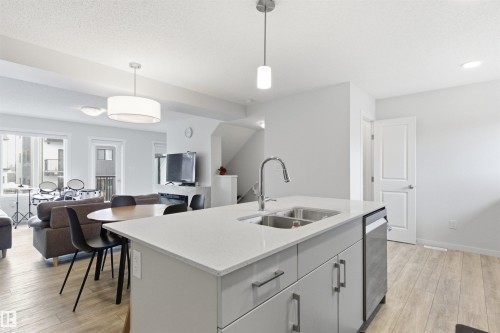 Kitchen island with a double basin stainless steel sink and a gooseneck faucet - 9 850 Secord Boulevard, Edmonton, AB - Indoor Photo Showing Kitchen With Double Sink