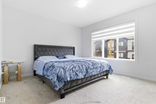 Spacious bedroom featuring light neutral wall paint, a large window with horizontal blinds, and carpeting - 9 850 Secord Boulevard, Edmonton, AB - Indoor Photo Showing Bedroom