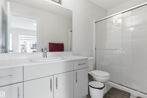 Bathroom featuring a white vanity with an integrated sink, polished chrome faucet, and ample storage cabinetry - 9 850 Secord Boulevard, Edmonton, AB - Indoor Photo Showing Bathroom