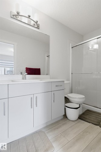 Contemporary bathroom featuring a light-toned vanity with dual sinks, a large mirror, and an overhead vanity light - 9 850 Secord Boulevard, Edmonton, AB - Indoor Photo Showing Bathroom