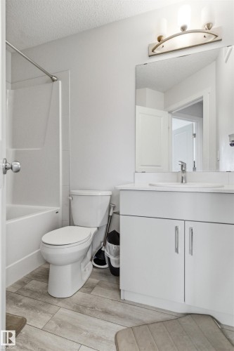 Bright bathroom featuring a white vanity with contemporary hardware, an integrated sink, and a framed mirror - 9 850 Secord Boulevard, Edmonton, AB - Indoor Photo Showing Bathroom