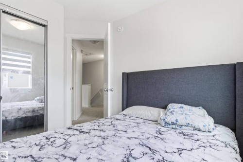 Room featuring a mirrored closet door, a flush-mount ceiling light fixture, and white wall finishes - 9 850 Secord Boulevard, Edmonton, AB - Indoor Photo Showing Bedroom