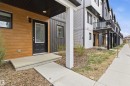 Modern townhome exterior featuring wood-look paneling, dark vertical siding, and a black front door with glass insert - 9 850 Secord Boulevard, Edmonton, AB  - Outdoor With Exterior 