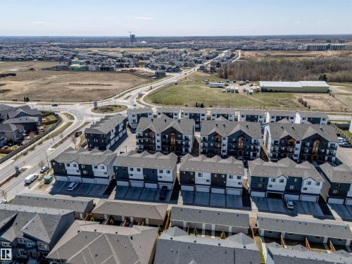 Modern townhome development featuring a dark gray and white facade, multiple balconies, and integrated garage spaces - 9 850 Secord Boulevard, Edmonton, AB - Outdoor With View