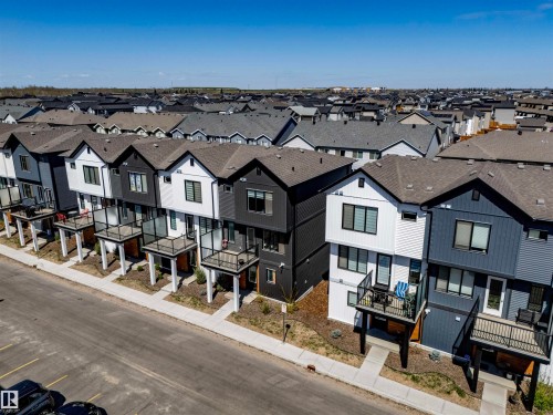 Modern townhome exteriors featuring contrasting dark and light siding, multiple balconies with glass railings, and a consistent architectural style - 9 850 Secord Boulevard, Edmonton, AB - Outdoor With Facade