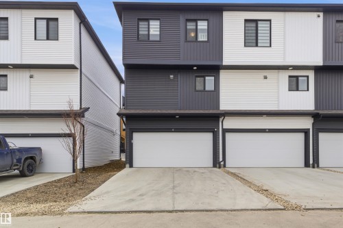 Contemporary multi-level townhome featuring a monochromatic facade with dark gray and white siding - 9 850 Secord Boulevard, Edmonton, AB - Outdoor With Exterior
