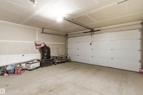 Spacious garage with a sectional overhead door, concrete flooring, and ceiling-mounted lighting - 9 850 Secord Boulevard, Edmonton, AB - Indoor Photo Showing Garage