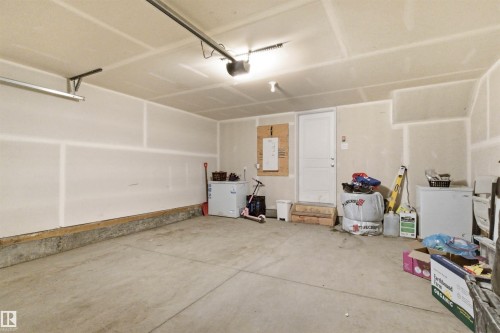 Spacious garage featuring a concrete floor, overhead lighting, and a white interior door - 9 850 Secord Boulevard, Edmonton, AB - Indoor Photo Showing Garage