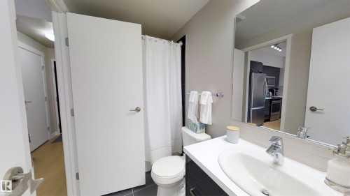 Modern vanity featuring a white countertop with integrated sink, chrome faucet, and a light-toned wood-finish backsplash - #1603 10410 102 Av Nw, Edmonton, AB - Indoor Photo Showing Bathroom