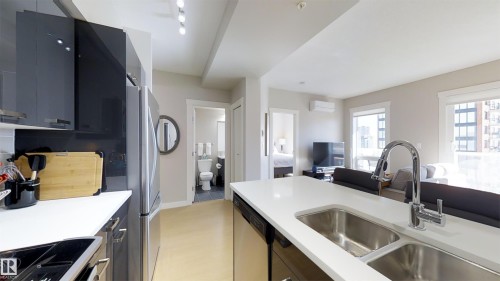 Modern kitchen featuring white countertops, stainless steel appliances, and dark flat-panel cabinetry - #1603 10410 102 Av Nw, Edmonton, AB - Indoor Photo Showing Kitchen With Double Sink