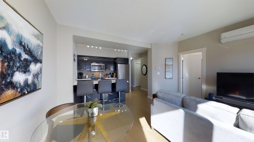 Open-concept living space featuring wood-finish flooring, a contemporary kitchen, and built-in air conditioning - #1603 10410 102 Av Nw, Edmonton, AB - Indoor Photo Showing Living Room