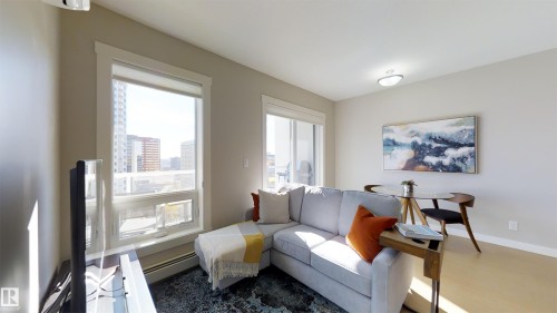 Living area with large windows, light gray walls, wood-finish flooring, and a flush-mount ceiling light - #1603 10410 102 Av Nw, Edmonton, AB - Indoor