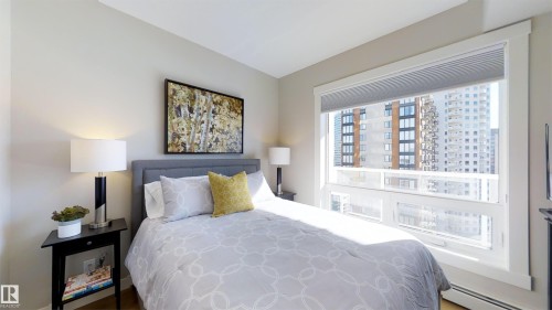 Bedroom featuring a wide window with cellular blinds, a gray upholstered headboard, and a built-in baseboard heater - #1603 10410 102 Av Nw, Edmonton, AB - Indoor Photo Showing Bedroom