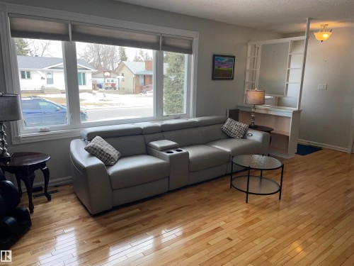 The living area features polished hardwood floors, a large picture window, and built-in shelving - 14212 30 Street, Edmonton, AB - Indoor Photo Showing Living Room