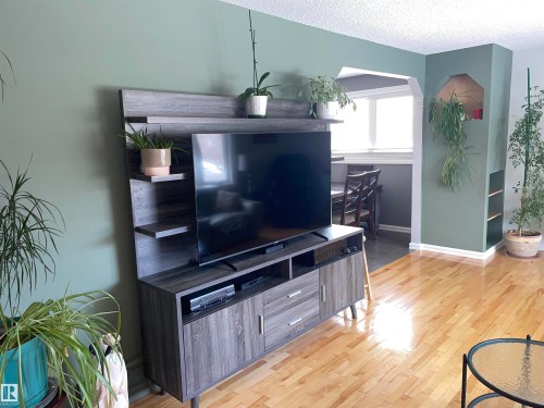 Living area featuring hardwood flooring, a decorative archway, and a built-in shelving unit - 14212 30 Street, Edmonton, AB - Indoor