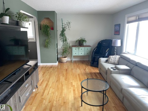 The living area features hardwood flooring, a large window providing natural light, and a built-in wall niche - 14212 30 Street, Edmonton, AB - Indoor Photo Showing Living Room