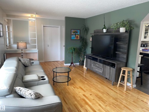 Living area featuring hardwood flooring, a built-in shelving unit, and a closet with bifold doors - 14212 30 Street, Edmonton, AB - Indoor Photo Showing Living Room