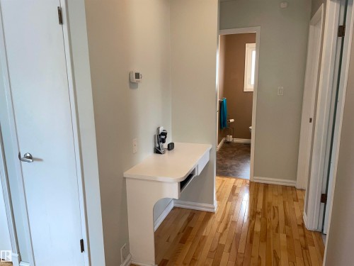This property features hardwood flooring throughout the hallway and a built-in white desk area - 14212 30 Street, Edmonton, AB - Indoor Photo Showing Other Room