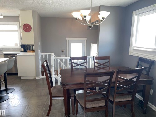 Spacious dining area featuring a chandelier, a window with natural light, and tiled flooring - 14212 30 Street, Edmonton, AB - Indoor Photo Showing Dining Room