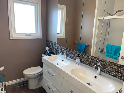 Bathroom featuring a double vanity with two undermount sinks, a mosaic tile backsplash, and a large mirror - 14212 30 Street, Edmonton, AB - Indoor Photo Showing Bathroom