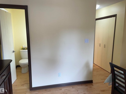 The property features hardwood flooring throughout, a wall with light switches, and a closet with bifold doors - 14212 30 Street, Edmonton, AB - Indoor Photo Showing Bathroom