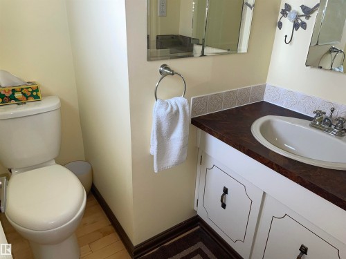 The bathroom features a toilet, a vanity with a sink, and a mirror - 14212 30 Street, Edmonton, AB - Indoor Photo Showing Bathroom