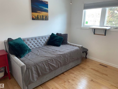 The room features hardwood flooring and a window with blinds, allowing for natural light - 14212 30 Street, Edmonton, AB - Indoor Photo Showing Bedroom