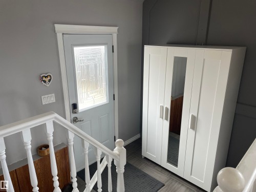 The entrance features a white door with a decorative glass panel, complemented by white trim and a white banister - 14212 30 Street, Edmonton, AB - Indoor Photo Showing Other Room