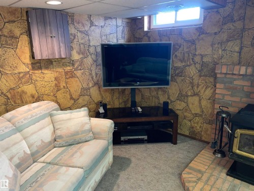 Living area featuring stone-look wall finishes, a brick hearth, and carpeted flooring - 14212 30 Street, Edmonton, AB - Indoor With Fireplace