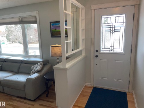 Welcoming entryway featuring a white door with decorative glass, light hardwood flooring, and a partial room divider with shelving - 14212 30 Street, Edmonton, AB - Indoor Photo Showing Other Room