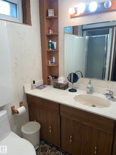 Bathroom featuring a vanity with a white countertop and wood cabinetry, a mirror, and overhead lighting - 14212 30 Street, Edmonton, AB - Indoor Photo Showing Bathroom