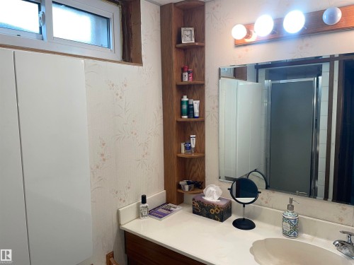 Bathroom vanity with an integrated sink, a large mirror, and overhead lighting - 14212 30 Street, Edmonton, AB - Indoor Photo Showing Bathroom