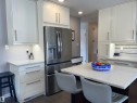 The property features a kitchen with white cabinetry, a stainless steel refrigerator, and light-colored countertops - 14212 30 Street, Edmonton, AB  - Indoor Photo Showing Kitchen 