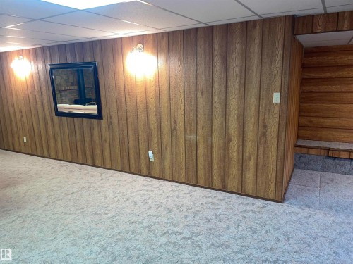 Spacious room featuring paneled walls, ceiling tiles, and carpeted flooring - 14212 30 Street, Edmonton, AB - Indoor Photo Showing Other Room