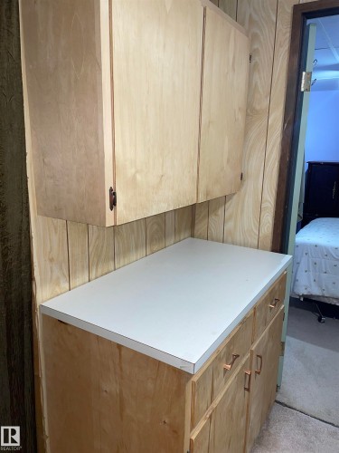 This area features wood-paneled walls, wooden upper and lower cabinetry, and a light-colored countertop - 14212 30 Street, Edmonton, AB - Indoor
